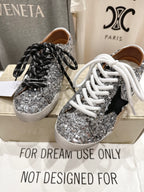 Pair of silver sequin sneakers with black and white laces, front view
