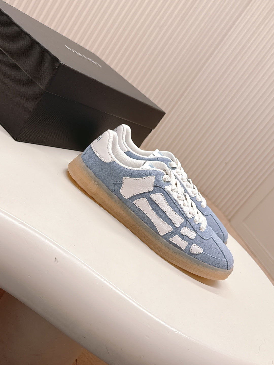Blue low-top sneaker with white contrast straps and lace-up closure.