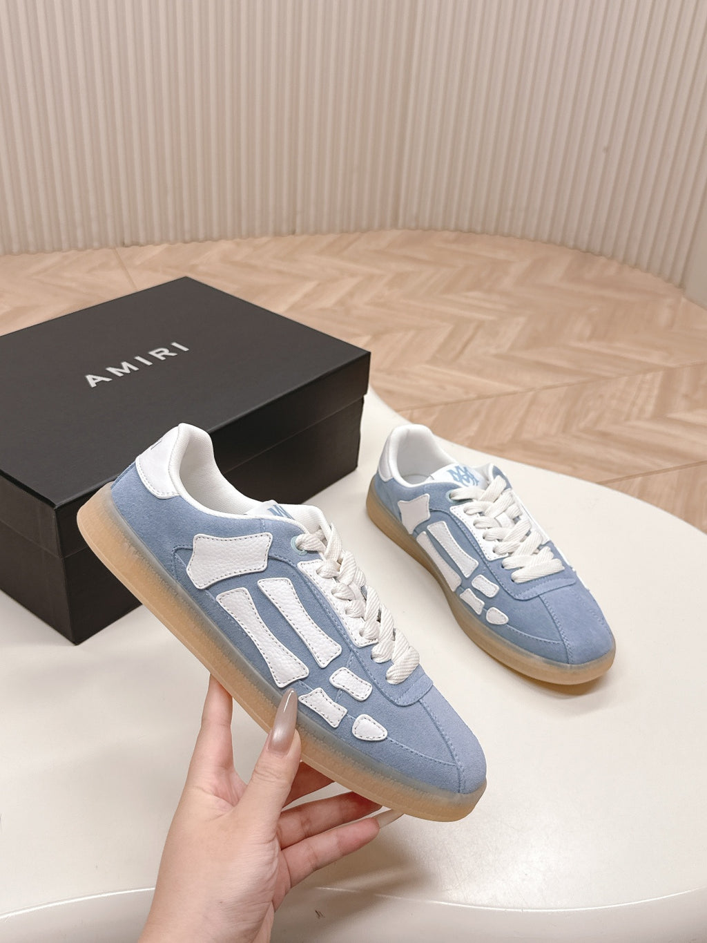 Two blue low-top sneakers with white logo-style overlays and lace-up fronts.