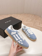 Two blue low-top sneakers with white logo-style overlays and lace-up fronts.