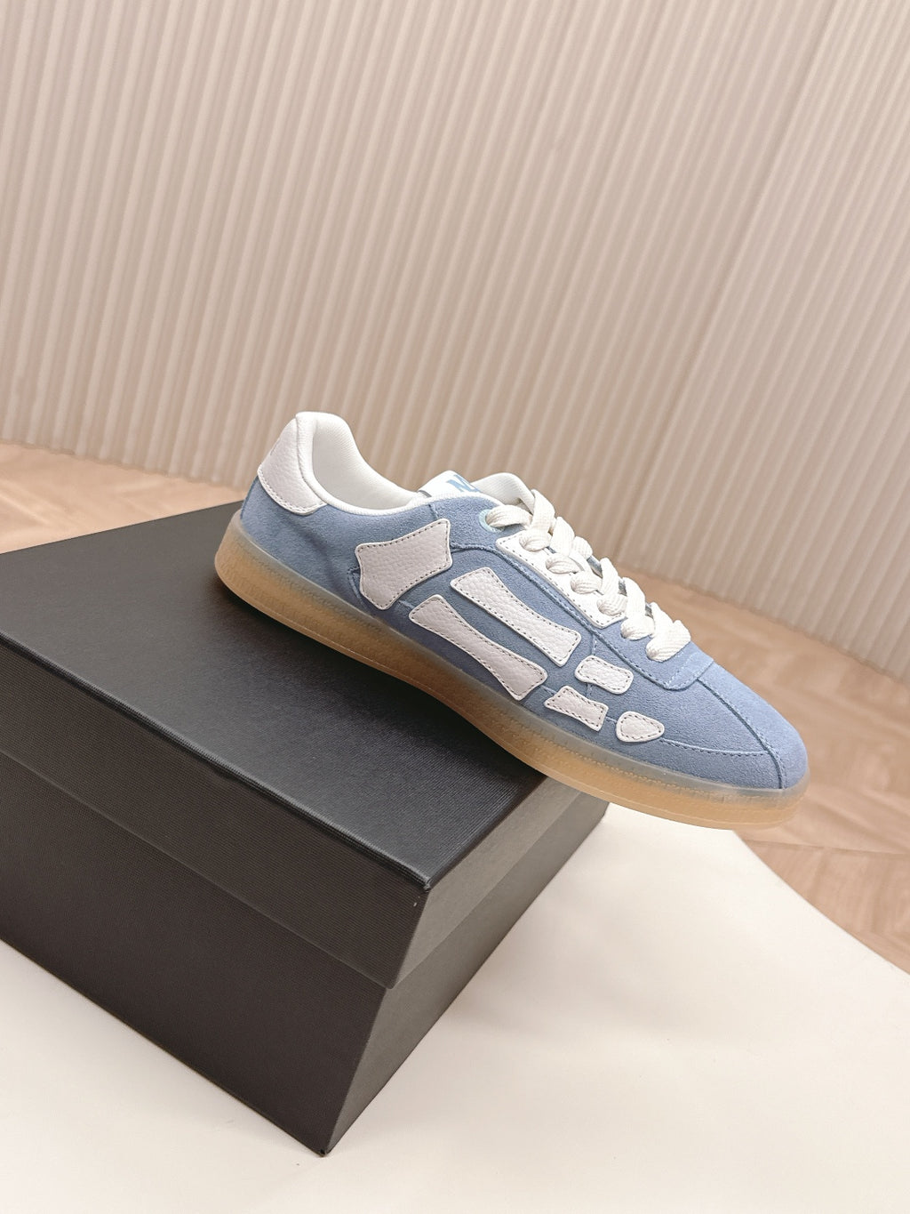 Blue suede-like low-top sneaker with white trim and lace-up front.