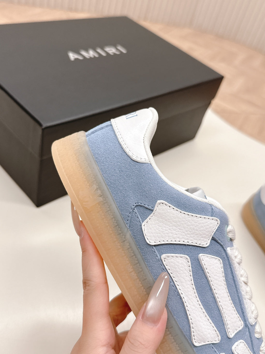 Blue low-top sneaker with white stitch trim and strap-style side design.
