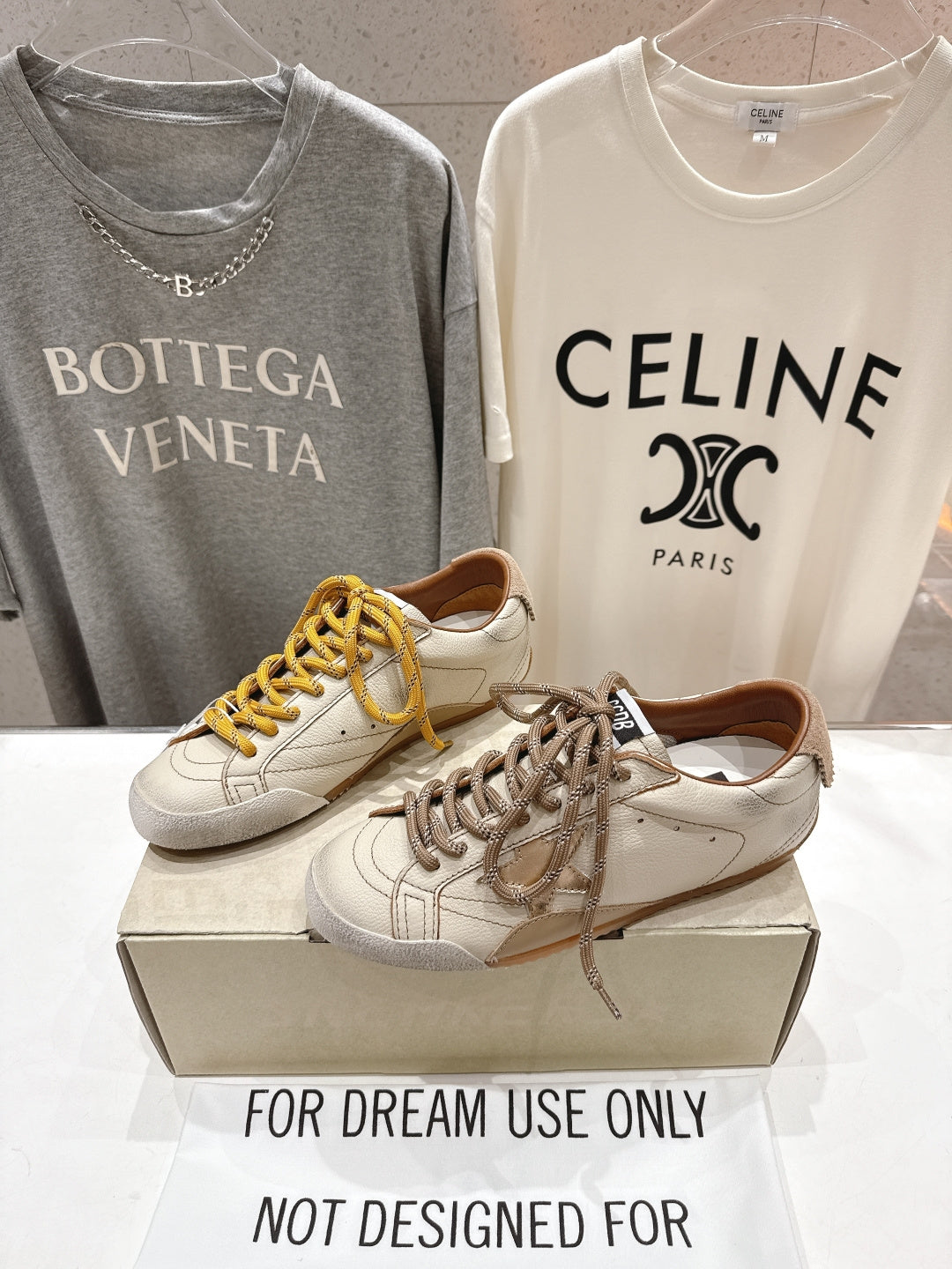 Golden Goose sneakers pair on display box, white leather with yellow and brown laces