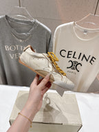 Golden Goose sneaker held in hand, white leather with yellow lace-up detail