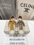 Golden Goose sneakers pair, white uppers with yellow and taupe laces on display box