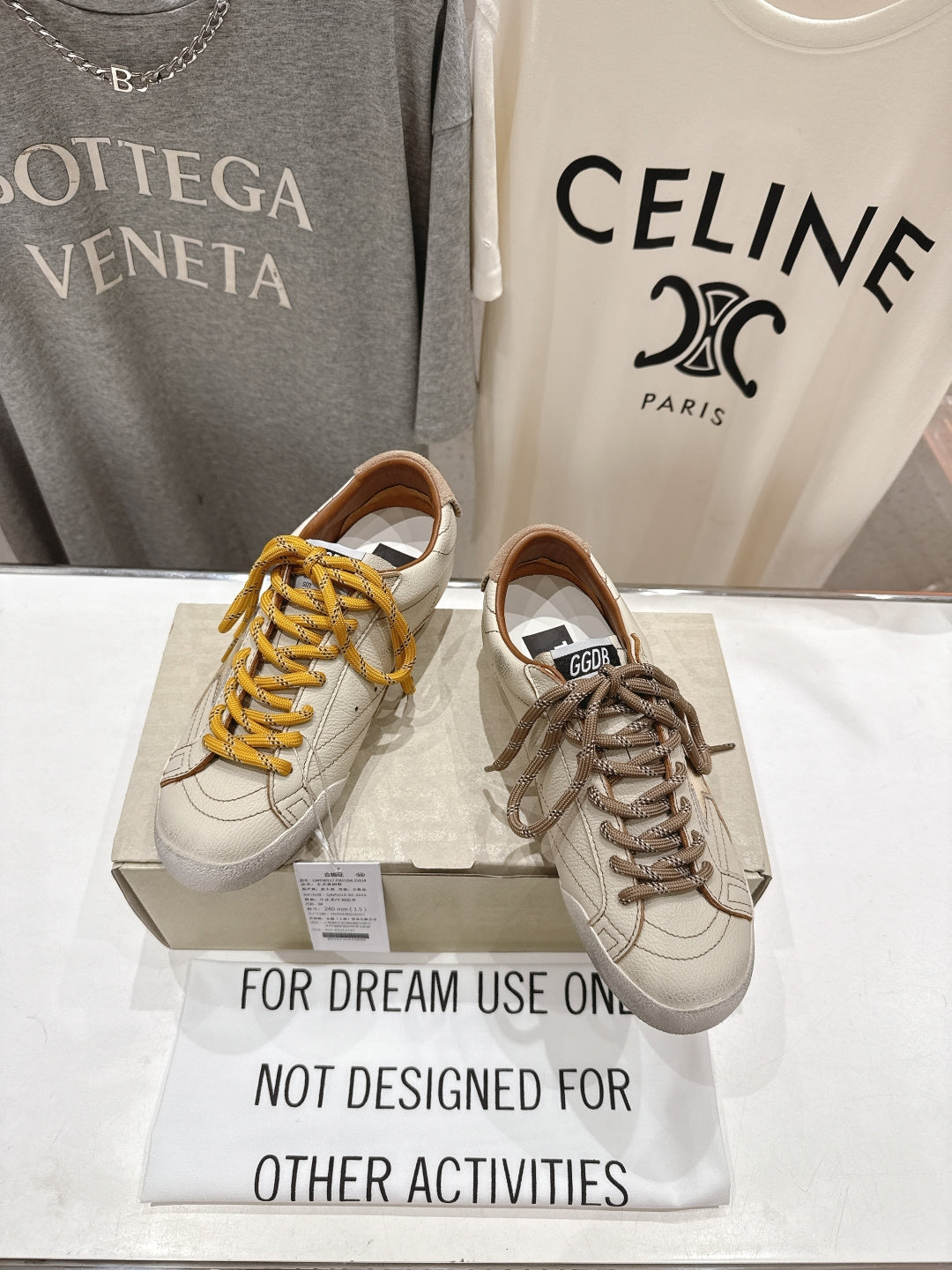 Golden Goose sneakers pair, white uppers with yellow and brown laces on display box