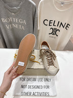 Golden Goose sneakers, hand showing textured sole of white shoe with yellow laces