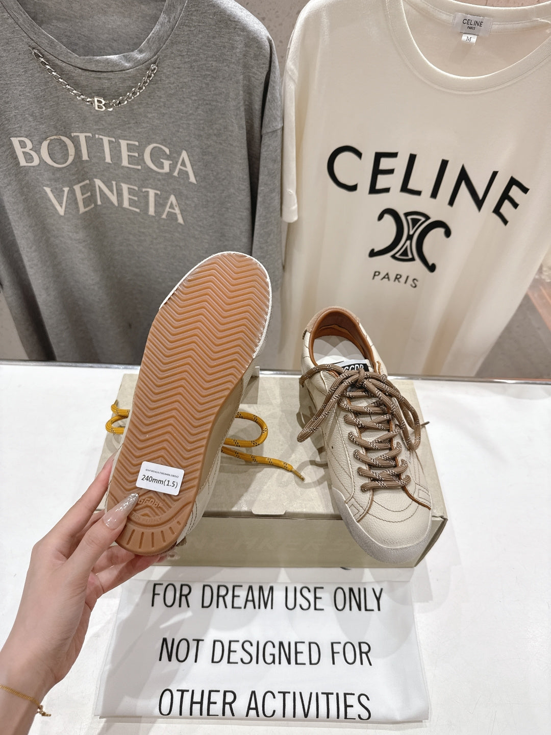 Golden Goose sneakers, hand showing textured sole of white shoe with yellow laces