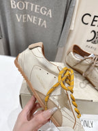 Golden Goose sneaker side view, white leather with yellow laces and tan accents