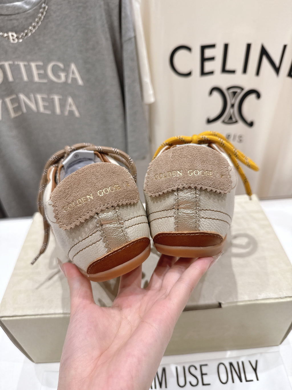 Golden Goose sneakers heel view, hand holding white shoes with tan soles and laces