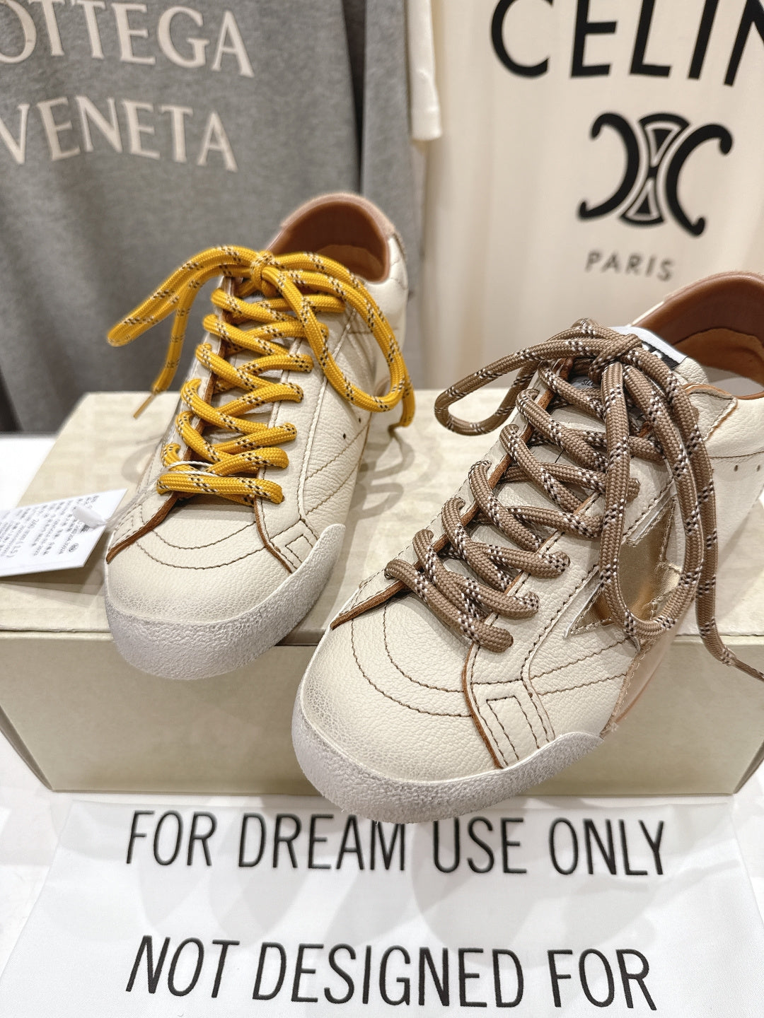 Golden Goose sneakers close-up on box, white uppers with yellow and gray-taupe laces