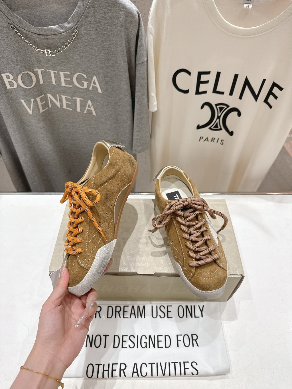 Golden Goose tan sneaker in hand with white star patch and brown laces