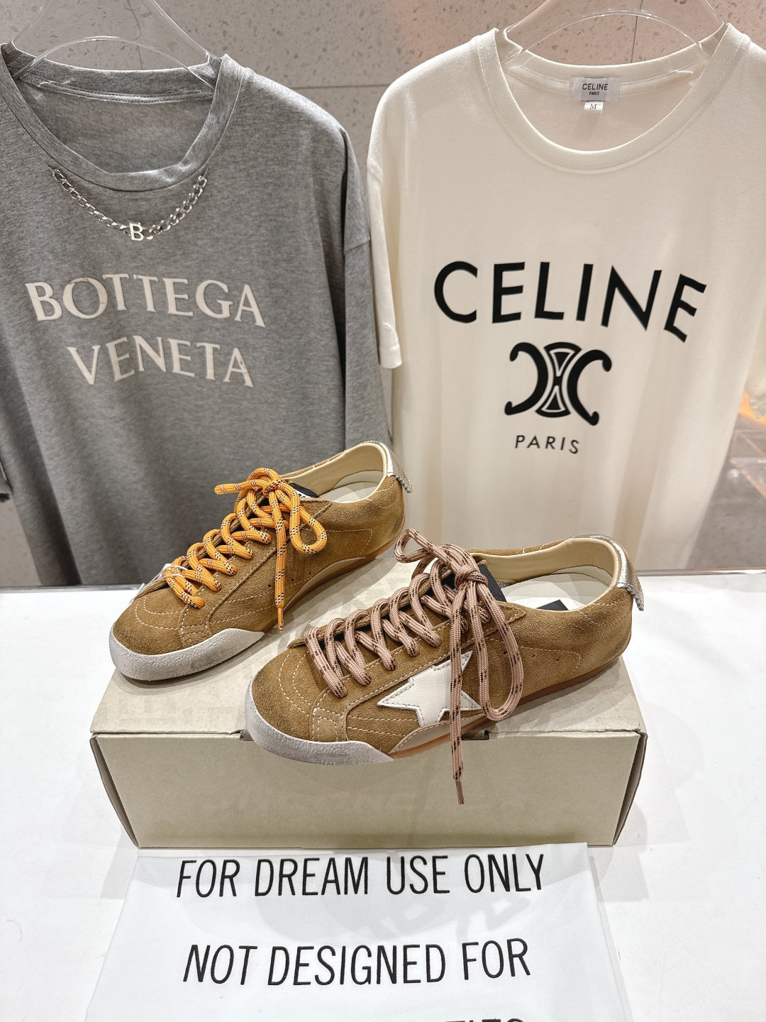 Golden Goose sneakers pair in tan with orange and brown laces, white star patches