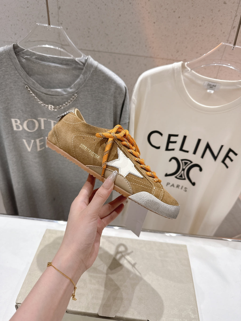 Golden Goose tan sneaker close-up with orange laces and white star applique