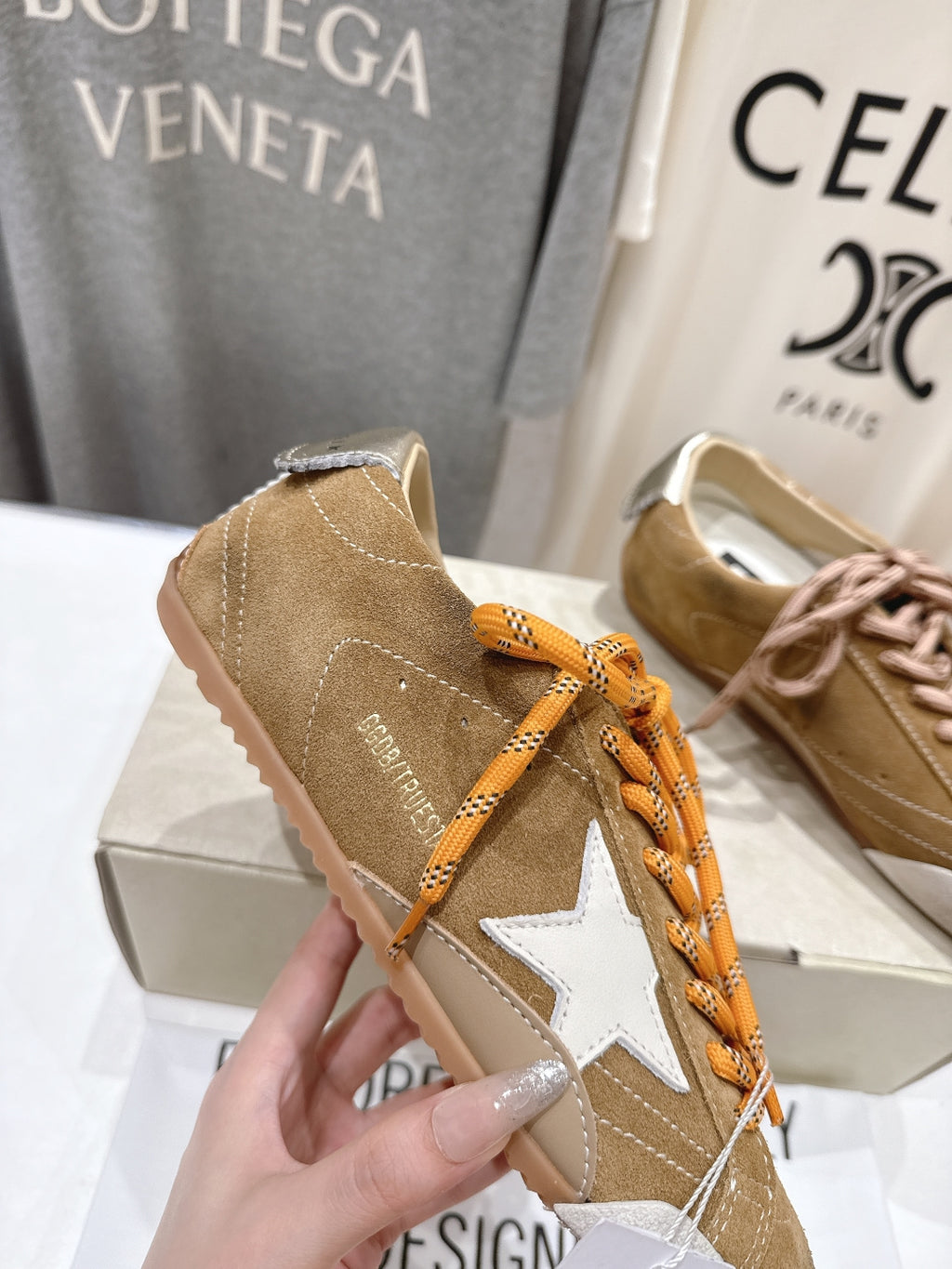 Golden Goose tan low-top sneaker detail with white star patch and orange laces