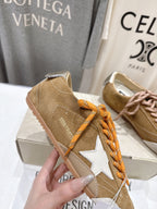 Golden Goose tan low-top sneaker detail with white star patch and orange laces