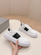 Prada unisex white sneakers with black side panel, hand holding one shoe