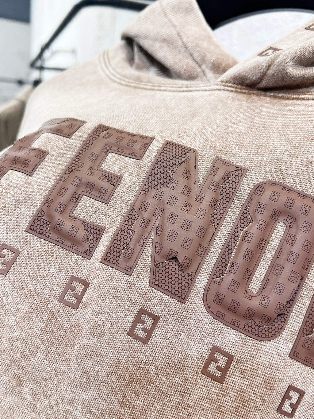 Beige FENDI hoodie with large front logo lettering and patterned print.