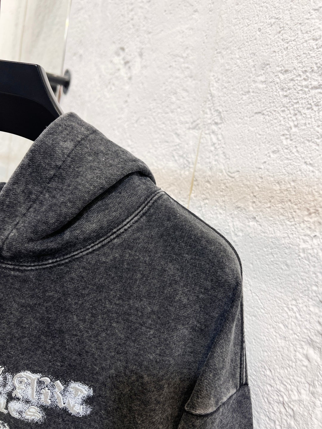Heather gray hoodie sleeve and shoulder seam detail with stitched collar edge
