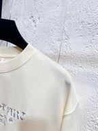 Close-up of cream sweatshirt shoulder and sleeve seam with blue print edge.