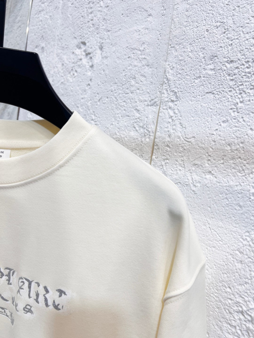 Close-up of cream sweatshirt shoulder and sleeve seam with blue print edge.