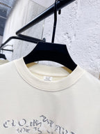 Close-up of crewneck collar and blue graphic print on cream sweatshirt.