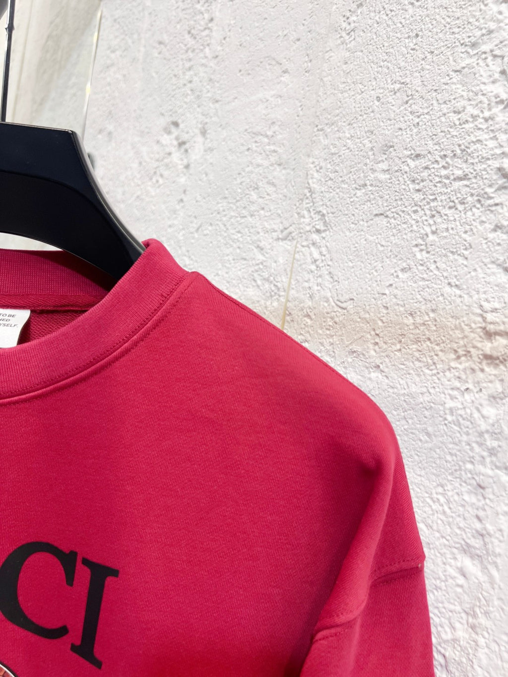 Bright pink Gucci sweatshirt shoulder and partial GUCCI lettering