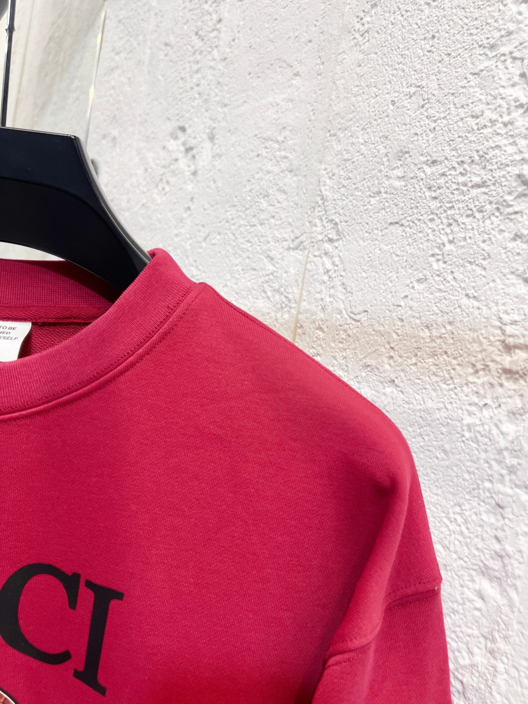 Bright pink Gucci sweatshirt shoulder and partial GUCCI lettering