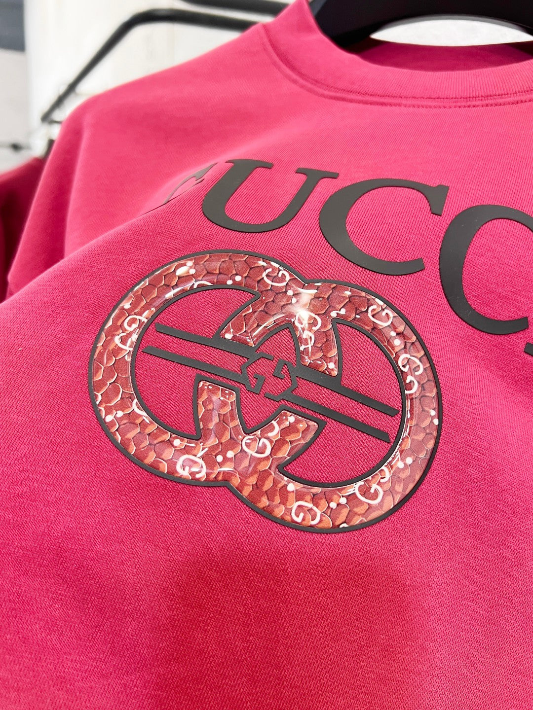 Bright pink Gucci sweatshirt close-up of oversized logo and crest