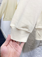 Cream sweatshirt sleeve cuff and hem with ribbed knit texture.