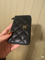 Chanel small zip pouch in dark quilted leather with gold CC emblem and side zipper.