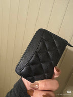 Chanel small zip pouch in dark quilted leather with gold zipper trim, angled view.