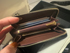 Chanel small bag open, showing card slots and zipped compartments with gold hardware.