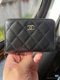 Quilted Chanel small bag with gold CC logo and zip closure on dark leather exterior.