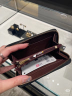 Chanel small bag open with burgundy lining, card slots, and gold zipper hardware.