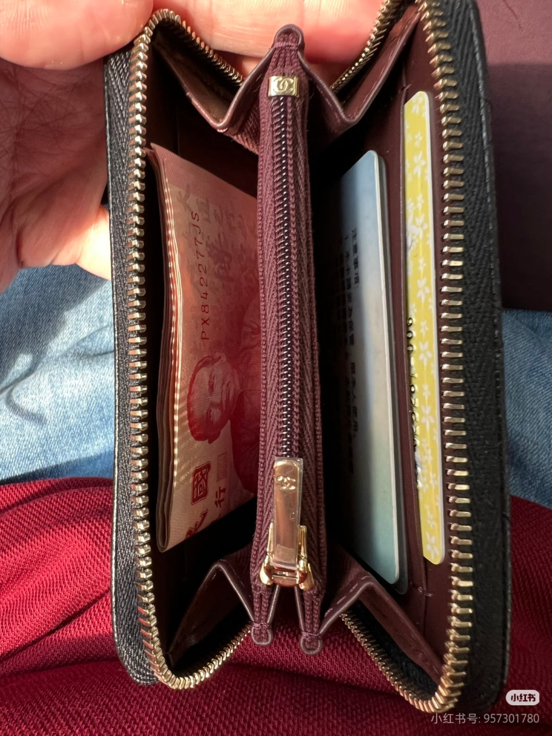 Chanel small bag open with burgundy lining, gold zipper edges, and card slots inside.