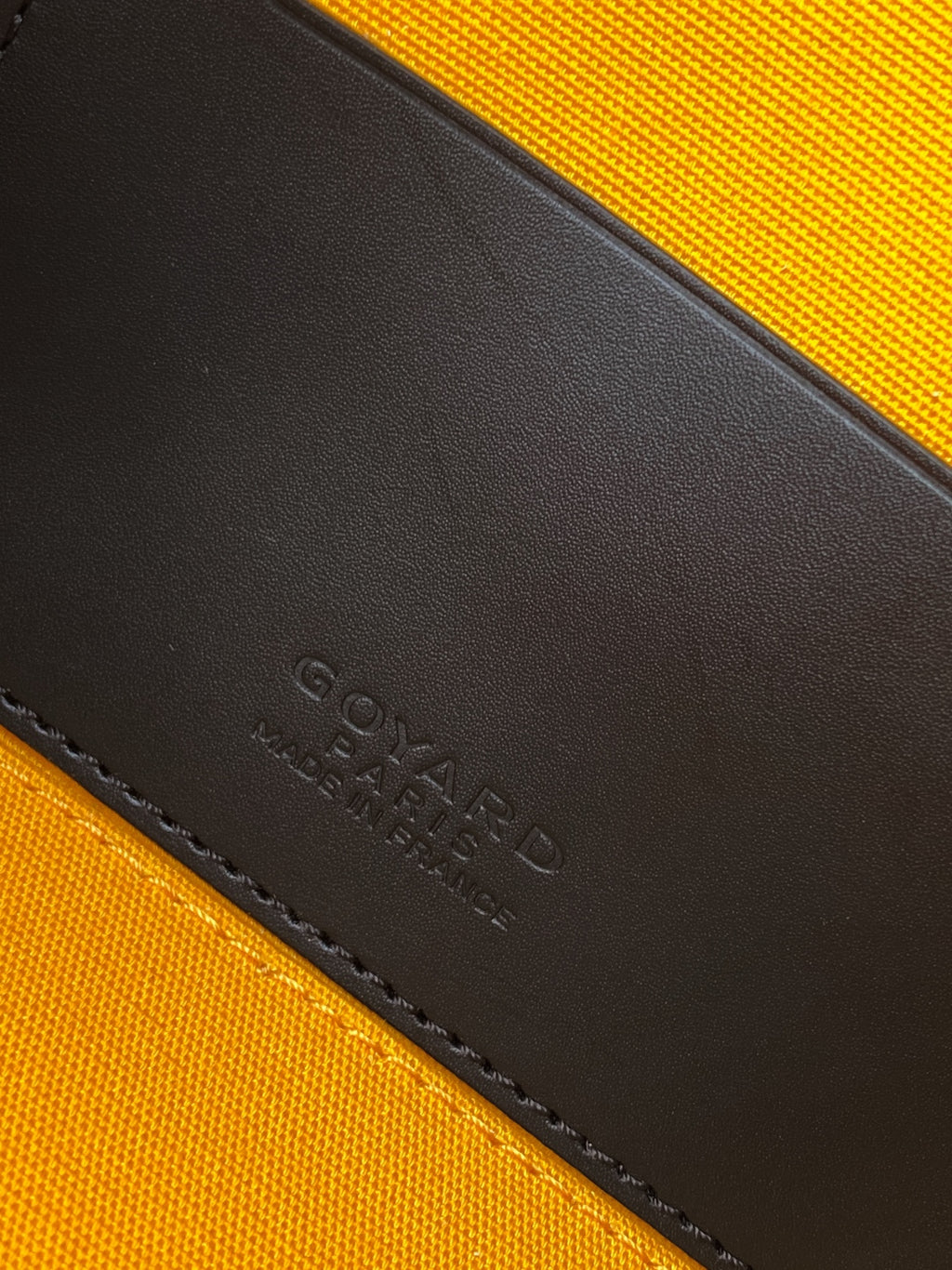 Embossed Goyard leather interior panel on black-and-orange bag