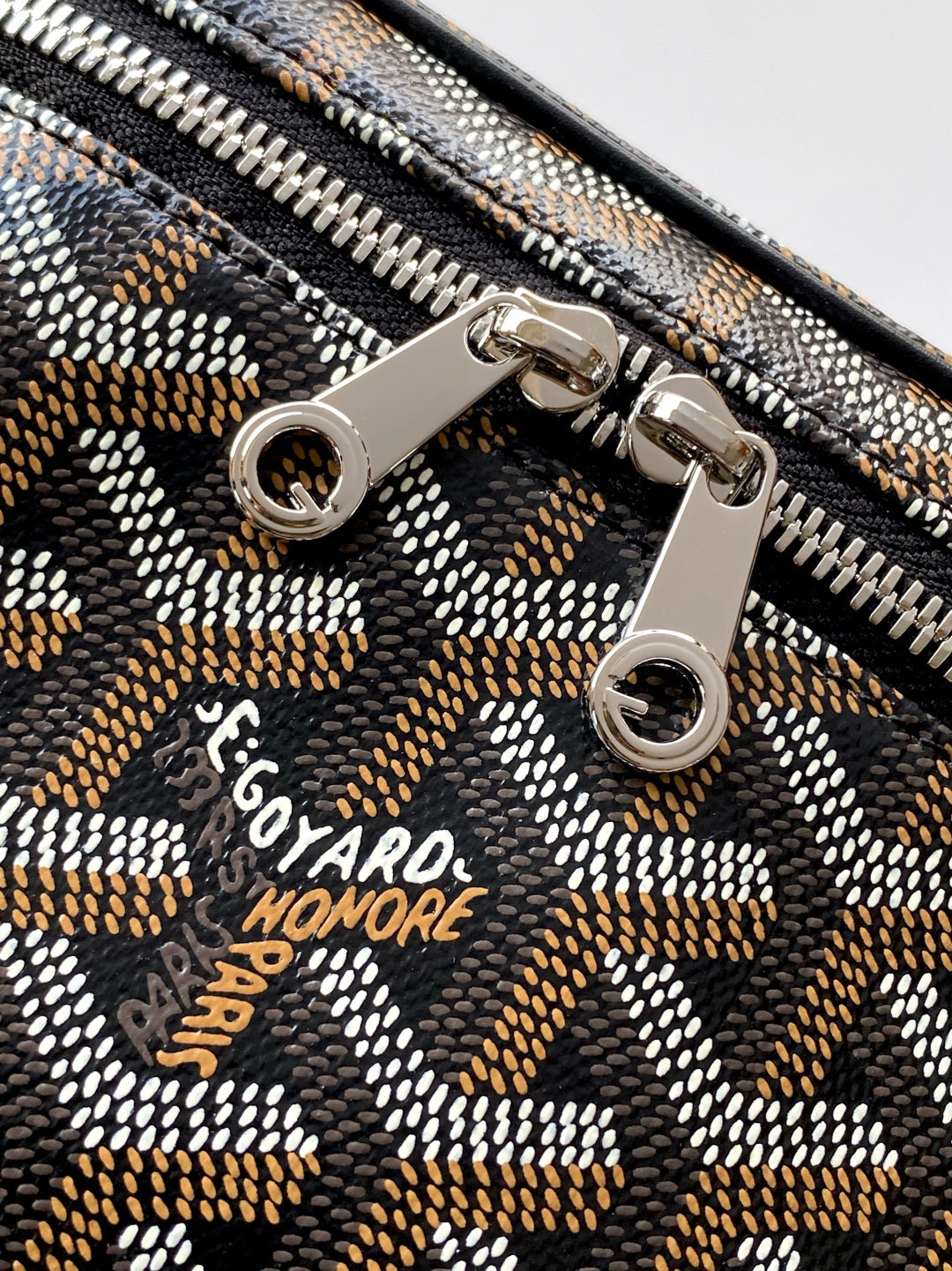 Goyard patterned zipper pull detail with engraved logo and metal rings
