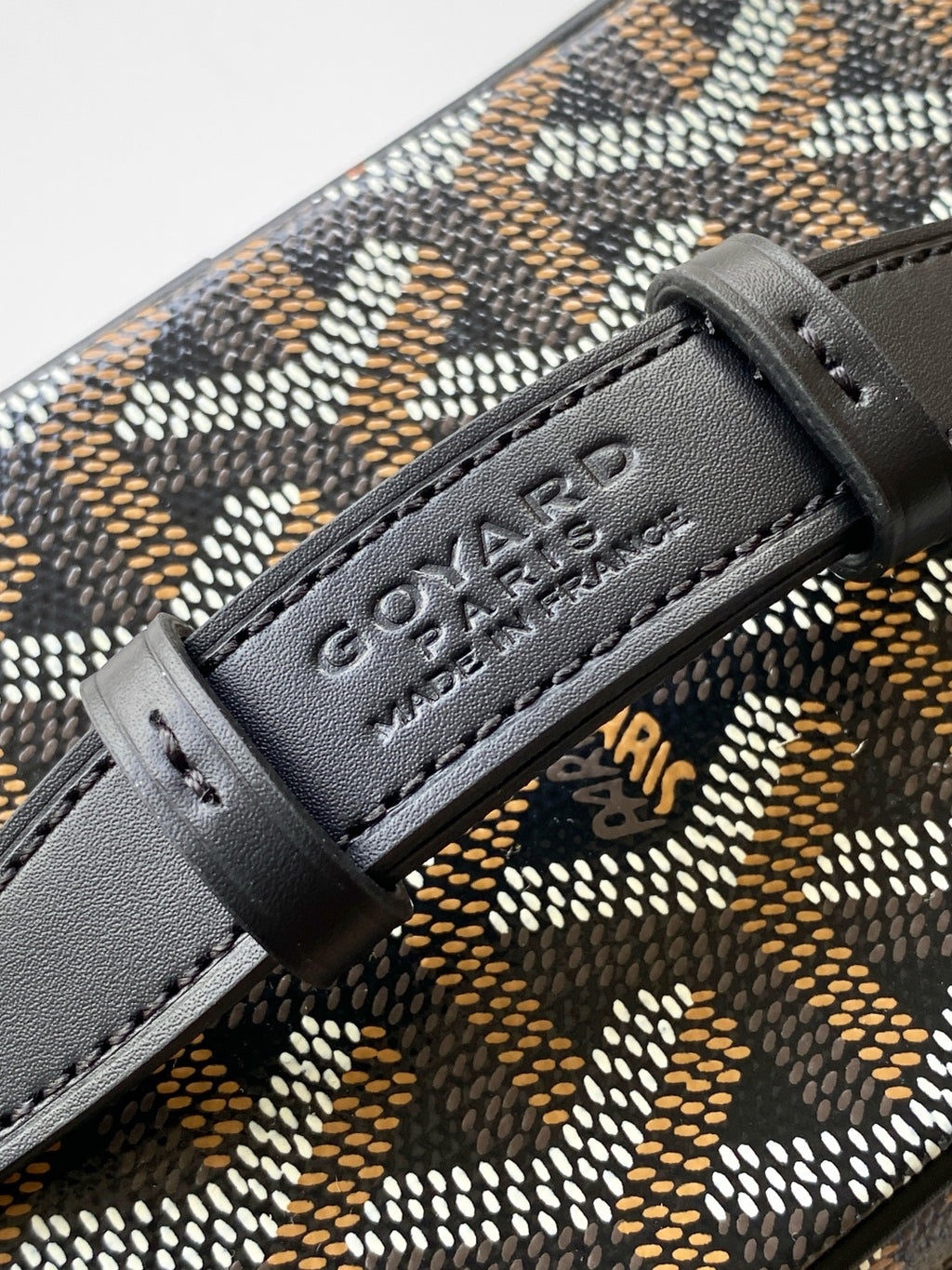 Goyard logo leather patch on patterned bag with stitched black trim