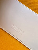 Goyard mini bag closeup of embossed logo on cream leather trim