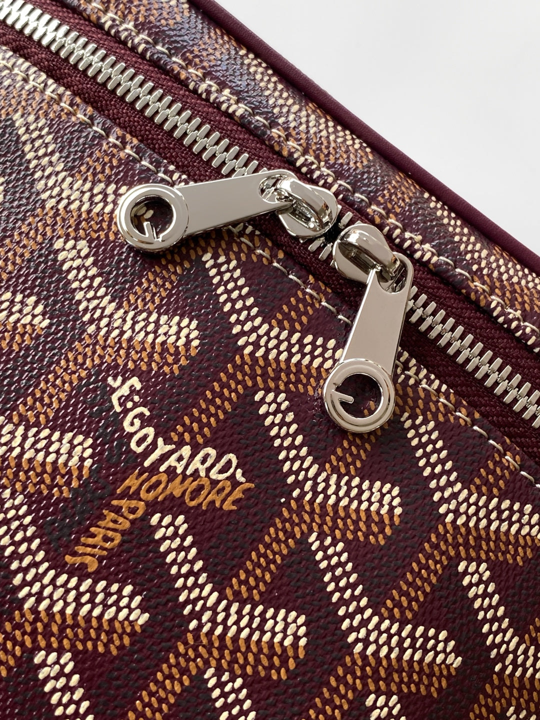 Goyard zipper hardware and logo patch on monogram canvas bag, close-up