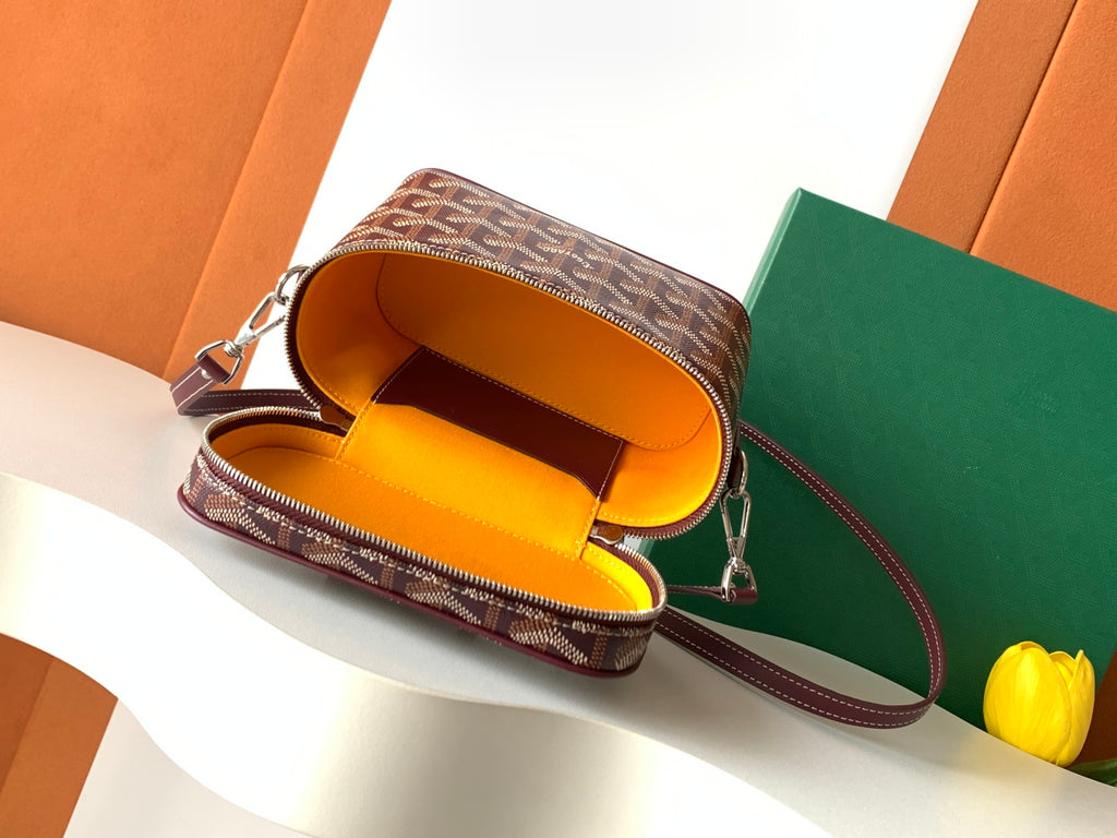 Goyard bag interior view with bright yellow lining and burgundy strap, top zip open
