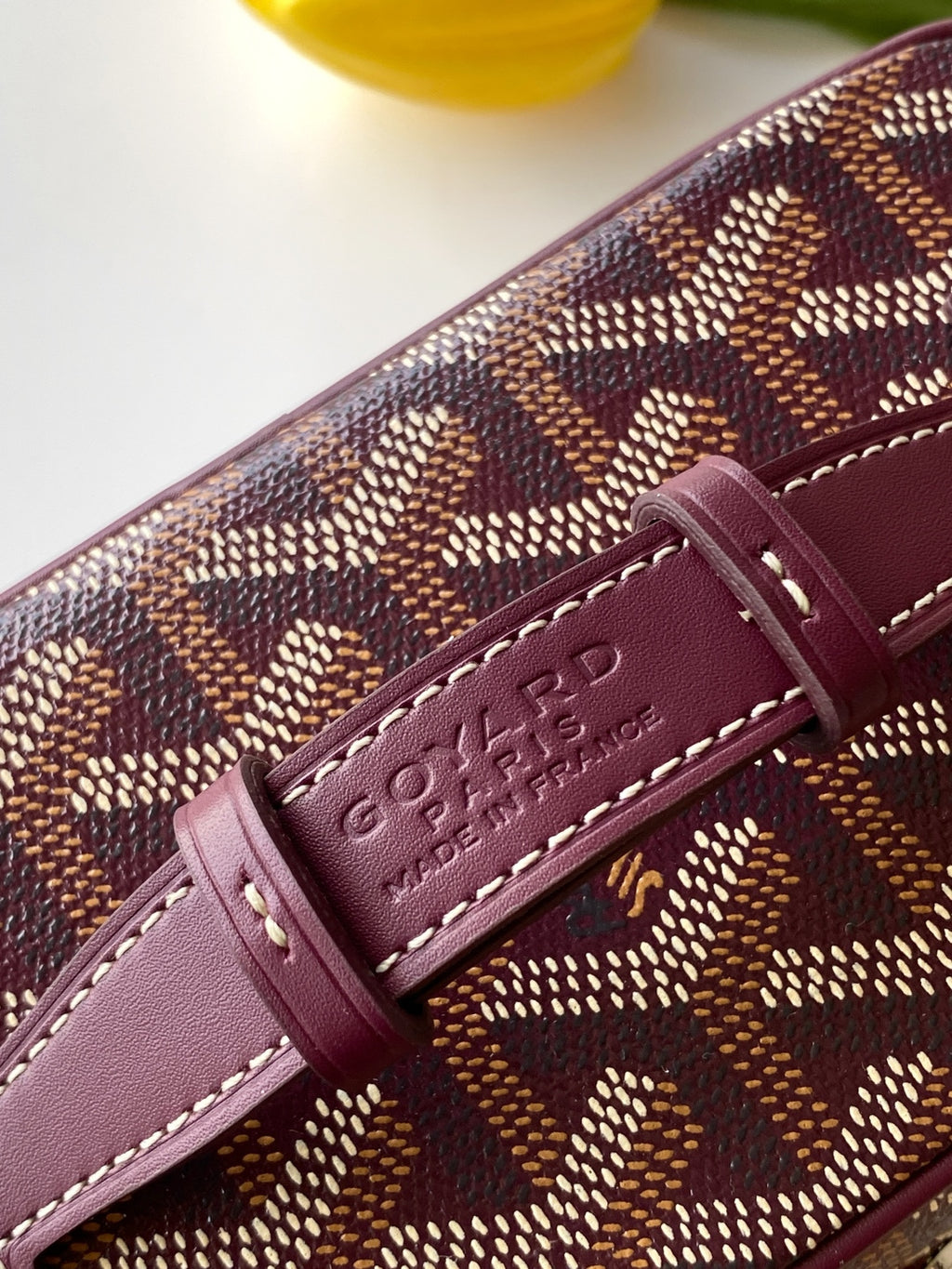 Goyard burgundy leather strap tab with embossed logo on patterned bag