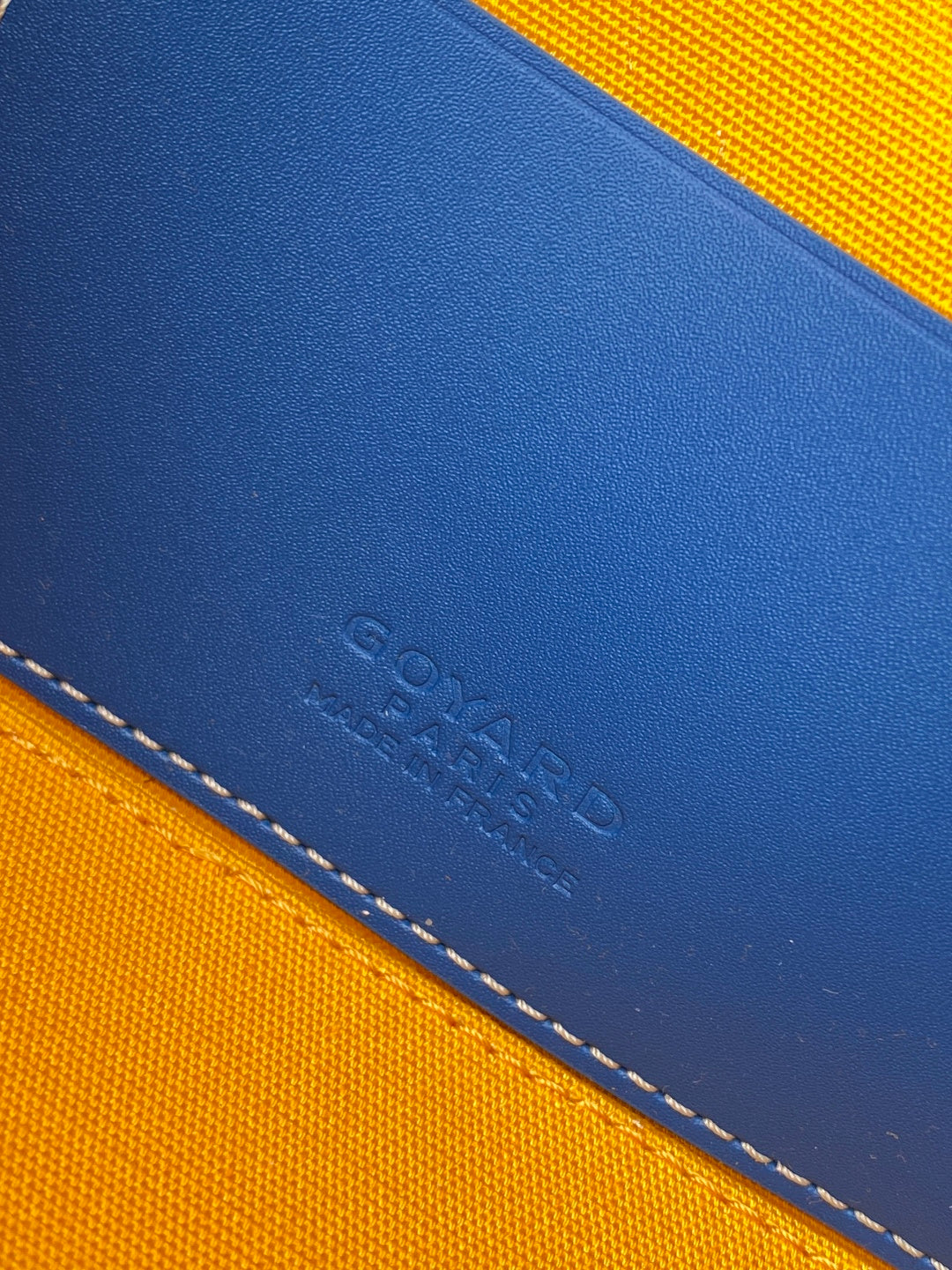 Goyard blue and yellow leather-trim bag corner with stamped logo and stitching