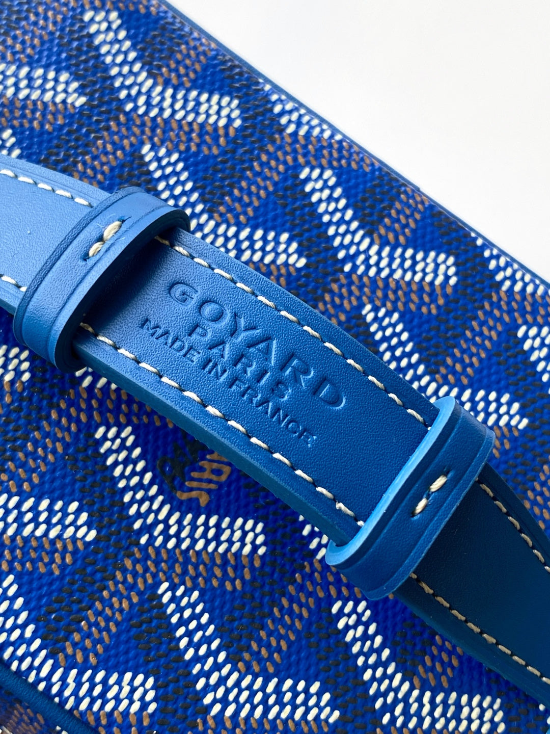 Close-up of Goyard blue leather strap tab with stamped logo