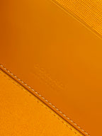 Yellow leather bag panel with embossed signature lettering and stitched edge