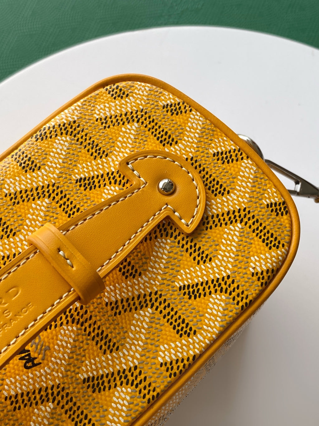 Yellow monogram bag front with leather strap loop and metal clasp hardware