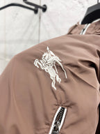 Taupe jacket shoulder with white horse logo patch and zip pocket