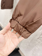 Taupe jacket hem with gathered drawstring detail and black star-shaped rivet