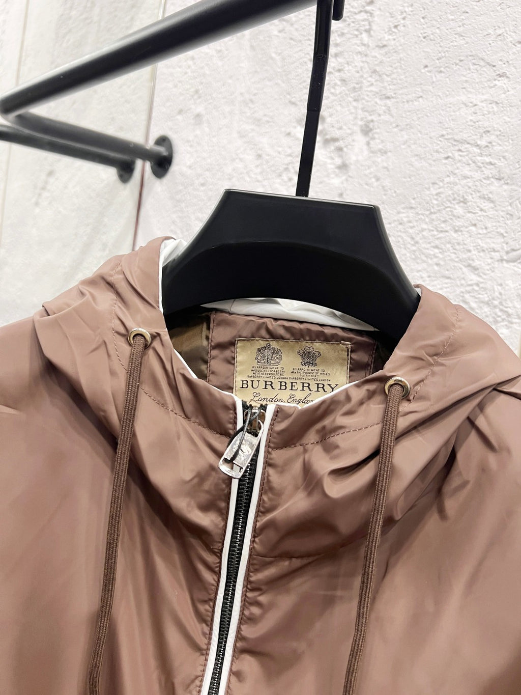 Taupe hooded jacket on hanger with visible inner lining and full front zip